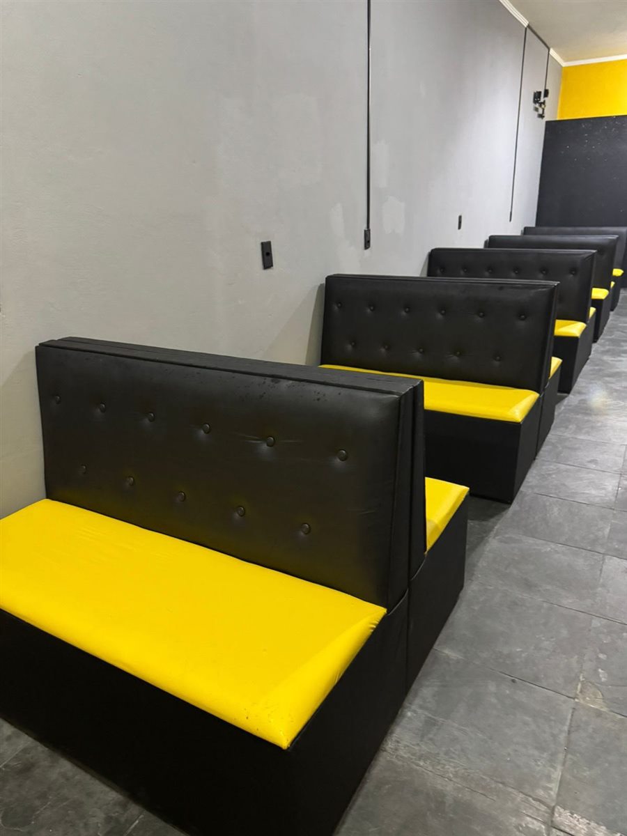 Fileira de sofás booth pretos com assento amarelo