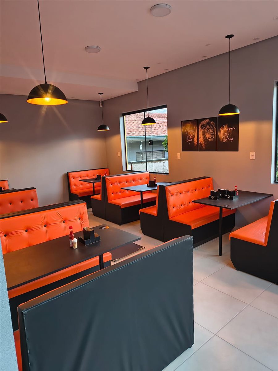 Restaurante com sofás booth laranja e mesas pretas